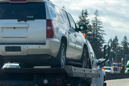 white suv vehicle on tow truck lifted for transportation
