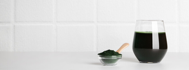 fresh green drink with spirulina in glass, spirulina powder with spoon on white background. self...