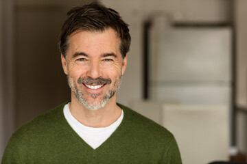 A portrait of a middle-aged bearded man smiling at the camera on a blur background