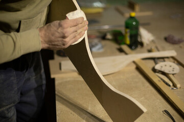 Carpenter grinds part out of wood. Board processing. Creation of furniture.