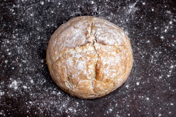 Fresh homemade crisp bread on black wooden table with wheat flour. Healthy baked bread. Traditional bakery Rustic style concept.