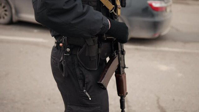 Street assault, military. Soldier in uniform with machine gun or assault rifle. Control point. Policeman stands with a machine gun controlling car traffic.