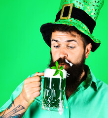 Patricks Day. Bearded man in leprechaun hat drinking green beer. March 17. Clover in beer. Closeup.