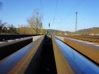 Bahnschienen vor Landschaft und Himmel bei Sonne am Abend im Winter