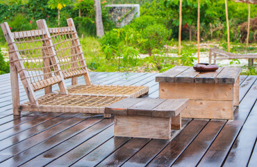 Empty wooden terrace with lounge beds and table. Wooden patio after rain. Wet terrace in tropical resort. Backyard in summer tourist resort. Outdoor furniture.