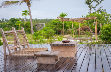 Empty wooden terrace with lounge beds and table. Wooden patio after rain. Wet terrace in tropical...