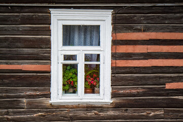 Obraz na płótnie Canvas flowers and curtains in the window of an old wooden house