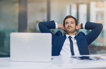 He makes business look easy. Shot of a young businessman looking relaxed with his hands behind his head.