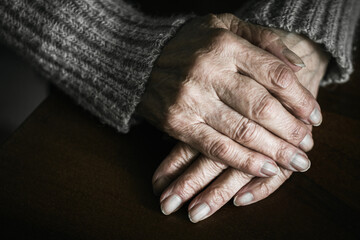 Close up of senior woman hands on table. Dramatic photography