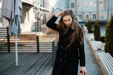 Obraz premium Beautiful lady in a black coat sitting with coffee to go. Casual street female portrait.