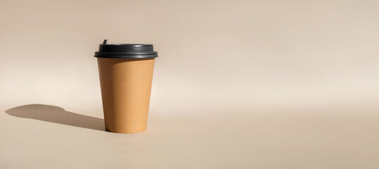 One Brown coffee paper cup. Mock-up with lid. Set of craft paper cups for coffee or tea on beige background. Front View. Zero waste, plastic free concept. Disposable Recycled cups. Long banner