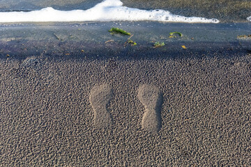footprints in sand near shoreline surf