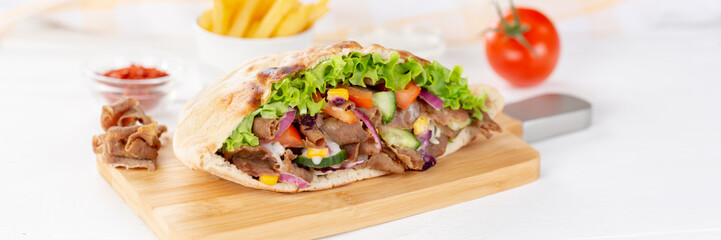 Döner Kebab Doner Kebap slice fast food in flatbread with French Fries on a wooden board panorama