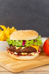 Hamburger Cheeseburger fastfood fast food with French Fries on a wooden board portrait format