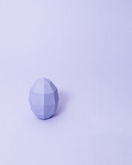 Geometric easter egg on pastel purple background with copy space. Minimal monochromatic easter concept.