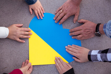 Human hands around a heart with the colors of the Ukrainian flag. Unity, solidarity and support for...