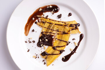 Dried bananas with nuts and chocolate on a white plate