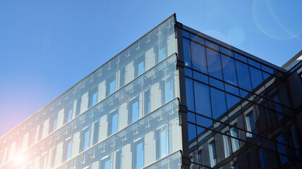 Perspective view to steel and  blue glass. Commercial modern city of future. Business concept of successful industrial architecture. The sunlight falling on the building.