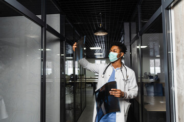 African doctor examines x-rays in a medical clinic. Black student in medical mask is studying and looking at ct scans.