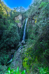 Mountain waterfall with milky water in tropical forest among green-blue rocks.