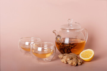 green tea in a teapot, ginger root, a piece of lemon on a beige background