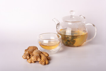 glass teapot with green tea, cup, ginger on a white background