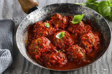 Meatballs in skillet with tomato sauce.