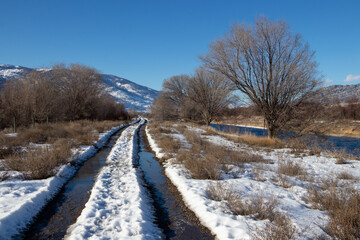 trail in the snow beside a river in the mountains