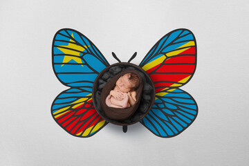 Tiny baby portrait with wings in color of national flag. Newborn photography concept. Democratic Republic of the Congo