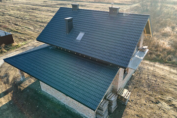Aerial view of house roof top covered with ceramic shingles. Tiled covering of building under...