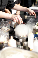 Fototapeta na wymiar chef innovando comida fusión con aromas de humo en plato con cubre platos de cristal