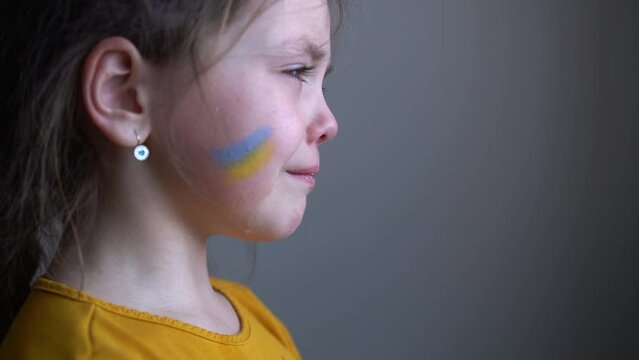 Upset Ukrainian girl kid crying protesting war conflict. Crisis, peace, stop aggression, child against Russian war