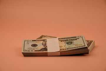 Two bundles of dollar bills on an orange table.