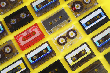 Retro audio cassette tape from the 80s and 90s on a yellow background.