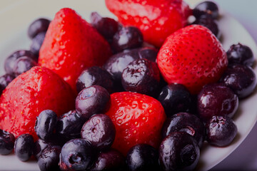 Obraz na płótnie Canvas Mixed berries on a white plate,shot close up and from above. 