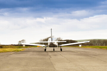 Rear view of a single engined private light aircraft taxiing for take-off. No people.