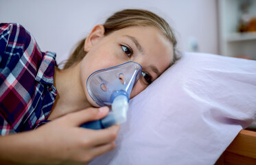 Little girl using inhaler at home. Health care concept