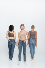 Fototapeta premium Young blonde woman posing near friends on grey background.