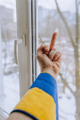 A Ukrainian man, being at home near a window in Ukraine under shelling in the war, shows an obscene...