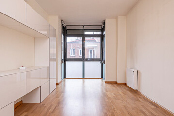 Empty living room with white mural cabinet and window in the background