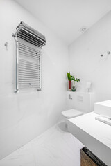 bathroom with white porcelain fixtures white tiled walls and marble floors and stainless steel towel radiator