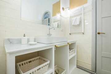 bathroom with white porcelain fixtures, white tile walls and black and white tile floors, white towel radiator, gray marble countertop and mirror