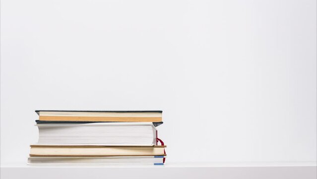 Stop motion animation of growing and shrinking stack of books isolated on white background. Educational or learning concept.
