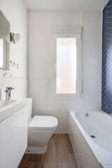 Toilet with white lacquered furniture, bathtub wall with blue tiles and the rest at half height in white