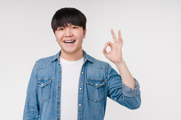 Smiling with braces asian korean man boy student showing okay gesture isolated in white background. Stomatology, dentistry concept - obrazy, fototapety, plakaty