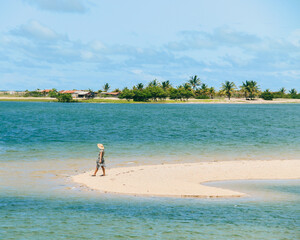 Fototapeta na wymiar Mulher caminhando na areia na Ilha de Guajiru, itarema, Cearà