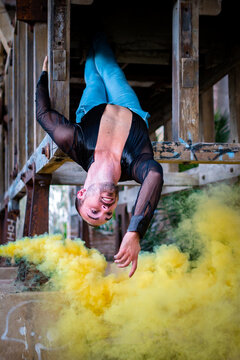 Retrato a joven bailarín de danza moderna haciendo danza moderna y jugando con humo de colores.