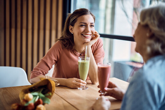 Happy mid adult woman enjoys in conversation with her mother on Mother's day in a cafe. - Powered by Adobe