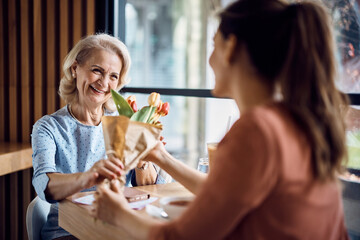 Happy senior woman receives bouquet of flowers from her daughter on Mother's day.