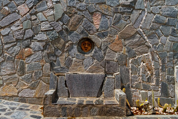 Stone seat with carved face on the wall